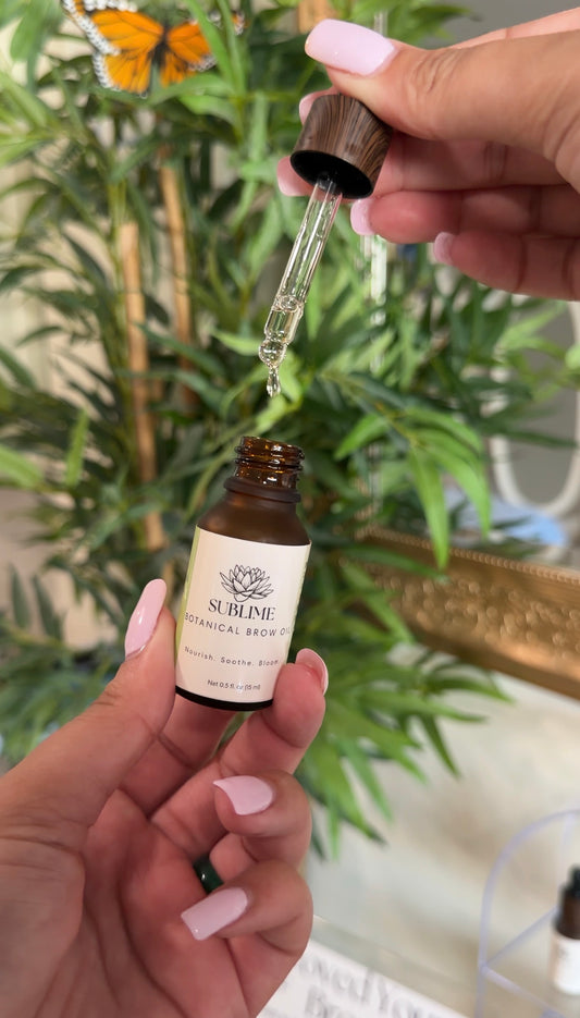 A drop of oil falling from the dropper above the open Sublime Botanical Brow Oil bottle